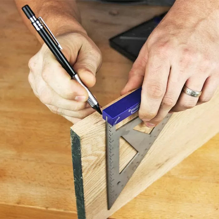 Person marking a wooden board with a square and pencil for precise woodworking measurement