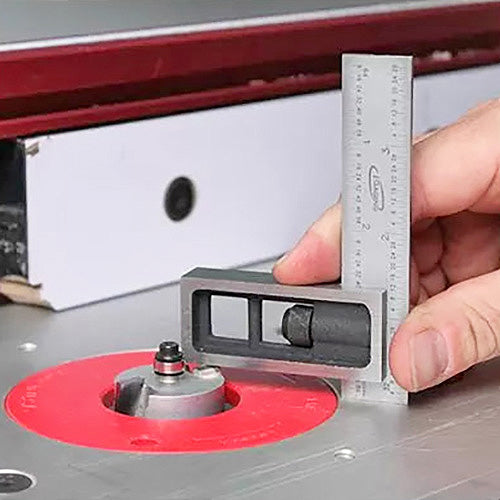 Hand using precision square to measure router bit height on a router table
