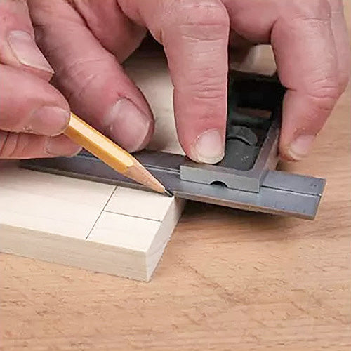 Woodworker using combination square and pencil to mark precise lines on a wooden board