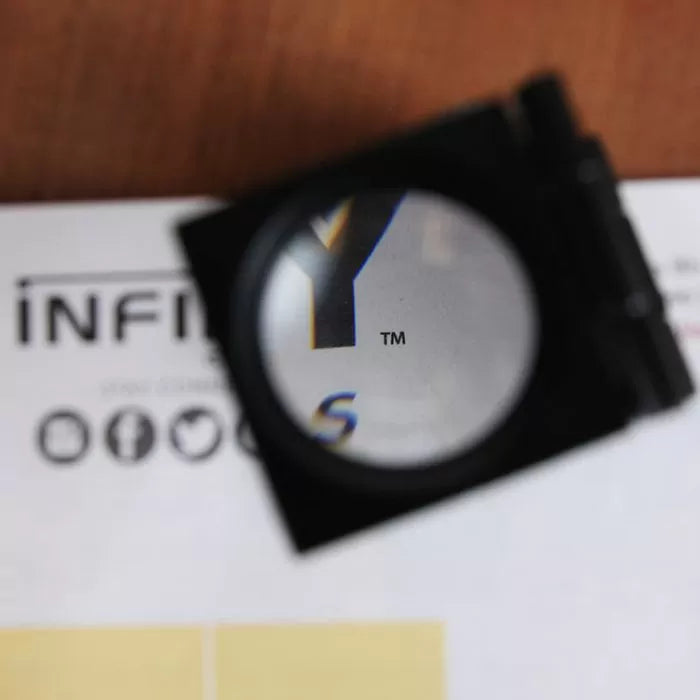Magnifying glass inspecting printed text on white paper, highlighting sharp print quality