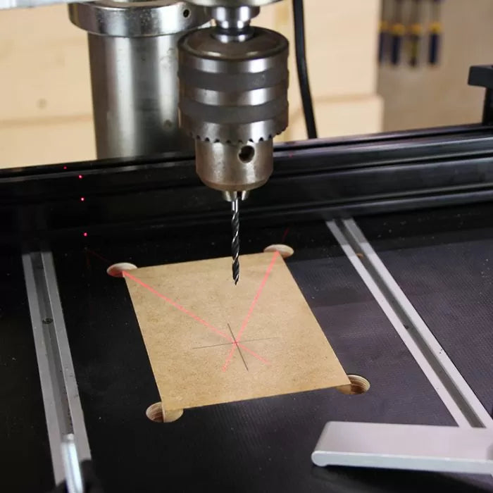 Drill press with crosshair laser guide aligning on marked wood for precision drilling