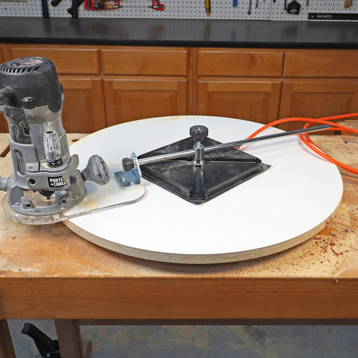 Woodworking router and circle cutting jig on round MDF board in workshop setting