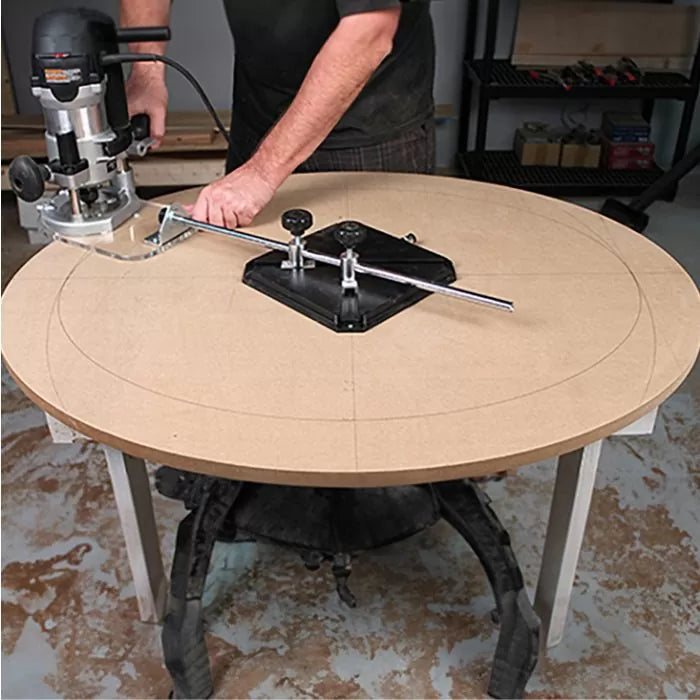 Woodworker using router circle cutting jig on MDF tabletop in workshop setting.