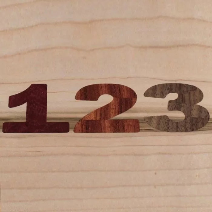 Wooden numbers 1, 2, and 3 cut from different hardwoods on a light wood background