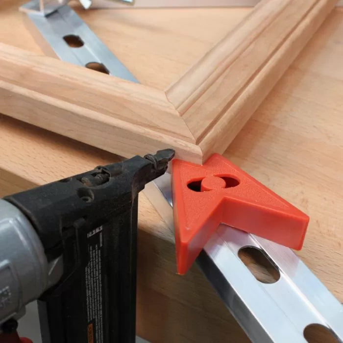 Wood picture frame clamped at 90-degree angle with corner clamp and a nail gun