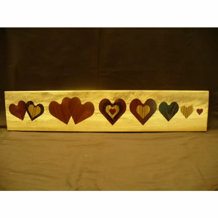 Woodworking inlay project with multiple heart-shaped patterns on a rectangular wood board