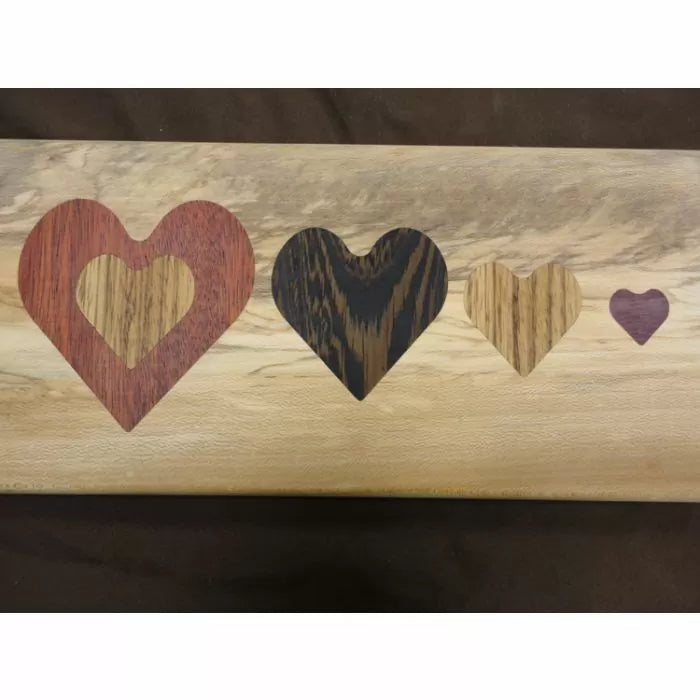 Wood inlay with four heart shapes in different colored woods on a light wood background