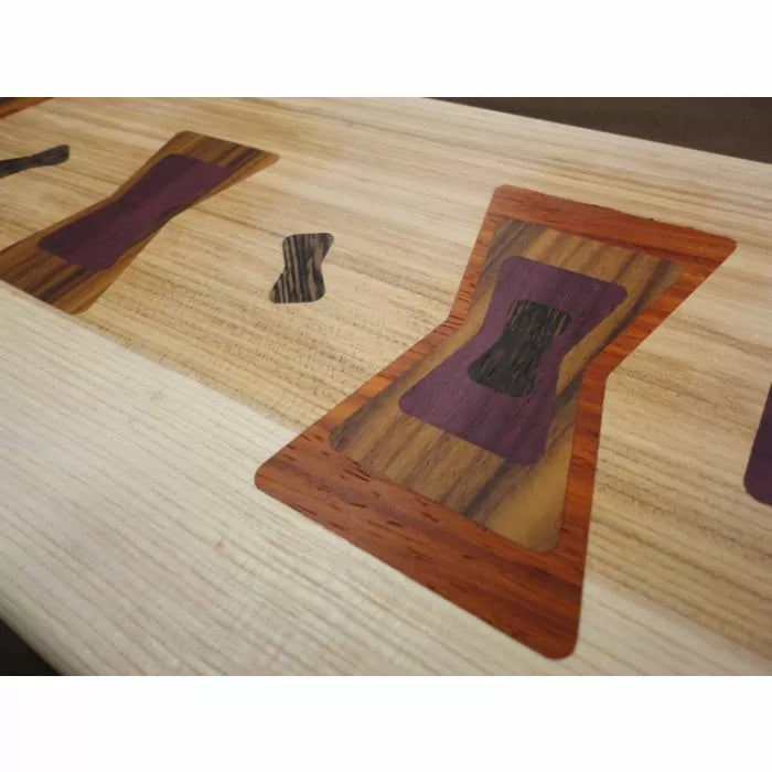 Close-up of wood inlays with butterfly joint patterns on a light wood surface