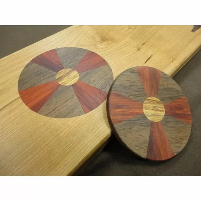 Wood inlay disc with segmented design in contrasting hardwoods on a light wooden board