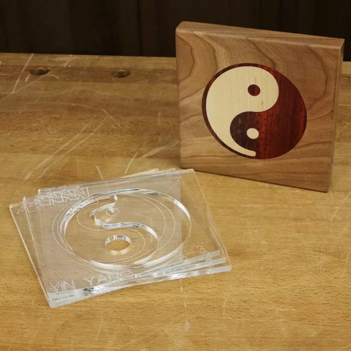 Yin Yang woodworking inlay template and finished wood inlay on a workbench