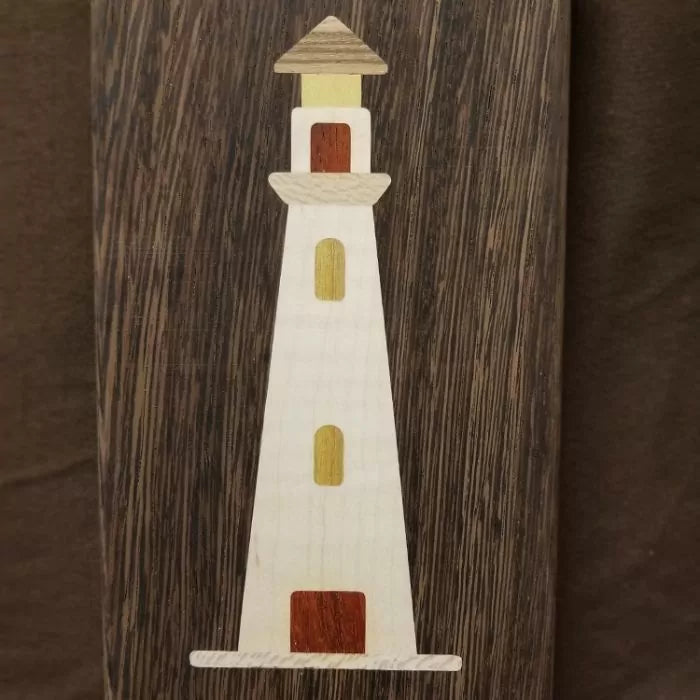 Wood inlay lighthouse design on dark wood background, marquetry woodworking project.