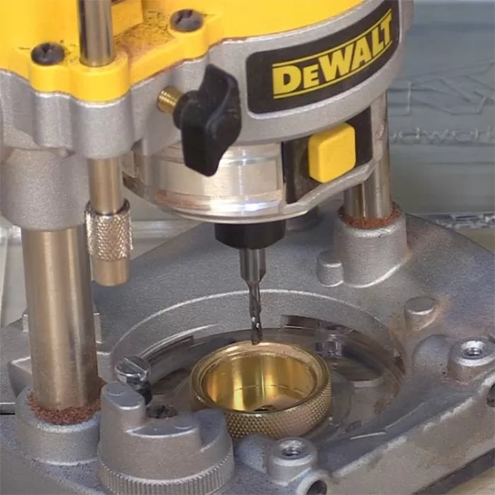 Close-up of a router base with brass guide bushing and drill bit installed