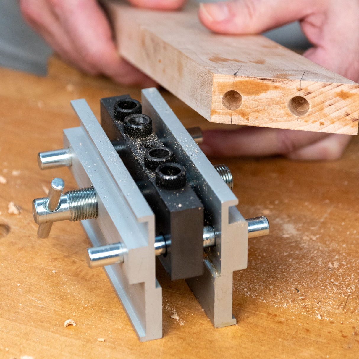 Self-centering dowel jig aligning drilled wood for precise woodworking joinery