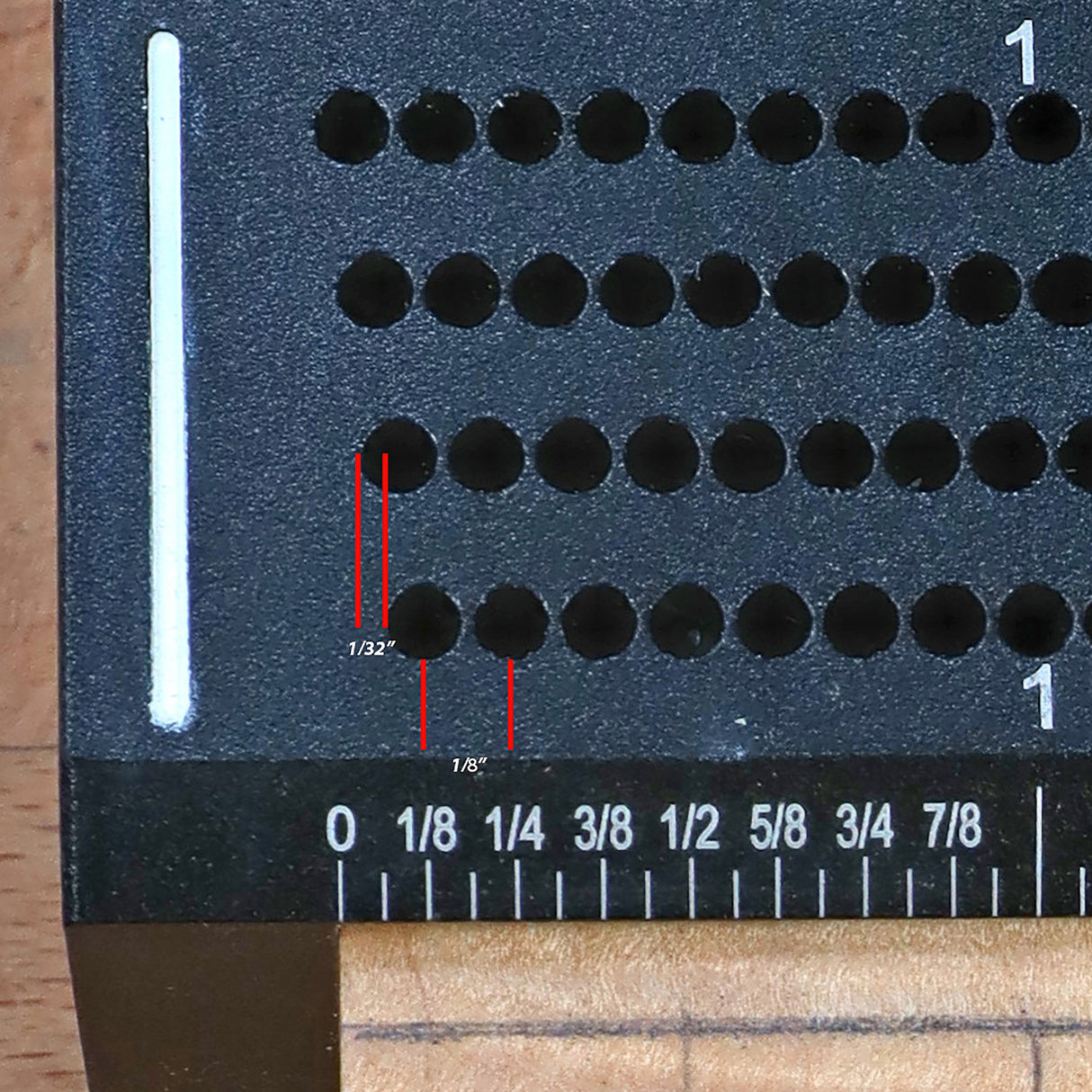Close-up of woodworking jig with offset hole guide and inch measurements for precise drilling.
