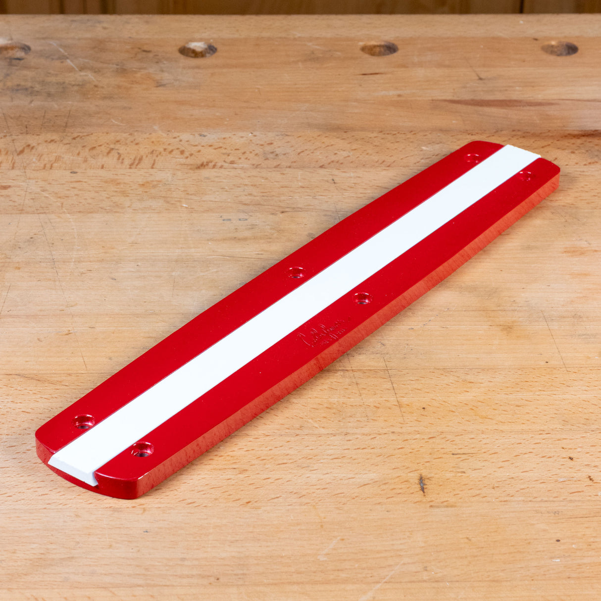 Zero clearance insert for miter saw, red with white stripe, on woodworking bench