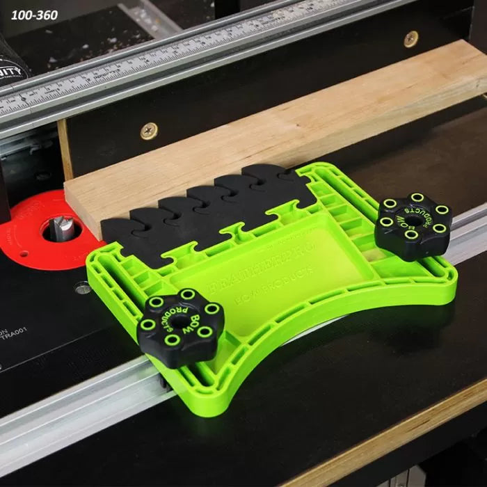 Green featherboard attached to router table guiding wood for precise woodworking cuts