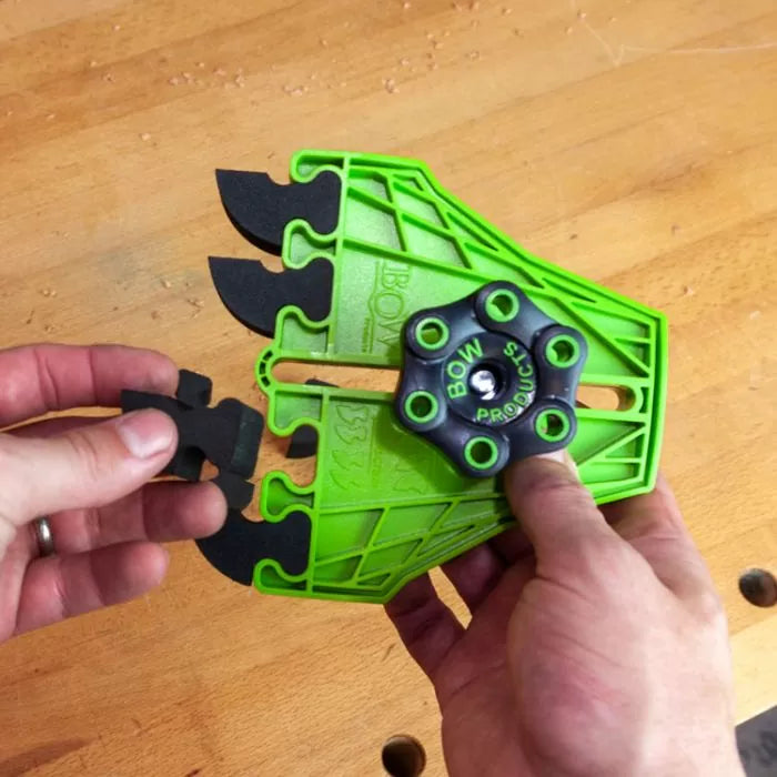 Hands replacing black feather inserts on green woodworking featherboard tool