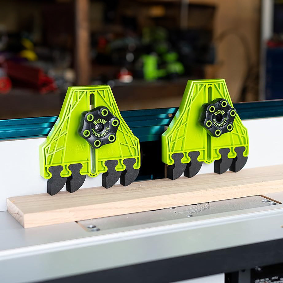 Green featherboards attached to a router table securing a wood board for woodworking