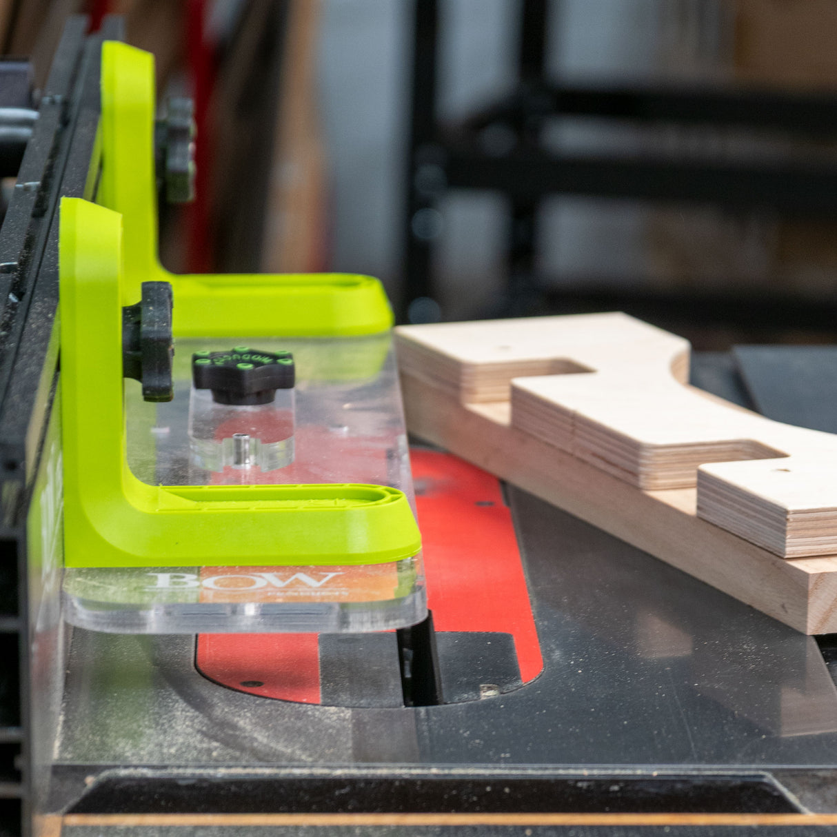 Table saw with bright green bow fence system and wooden workpiece for woodworking safety