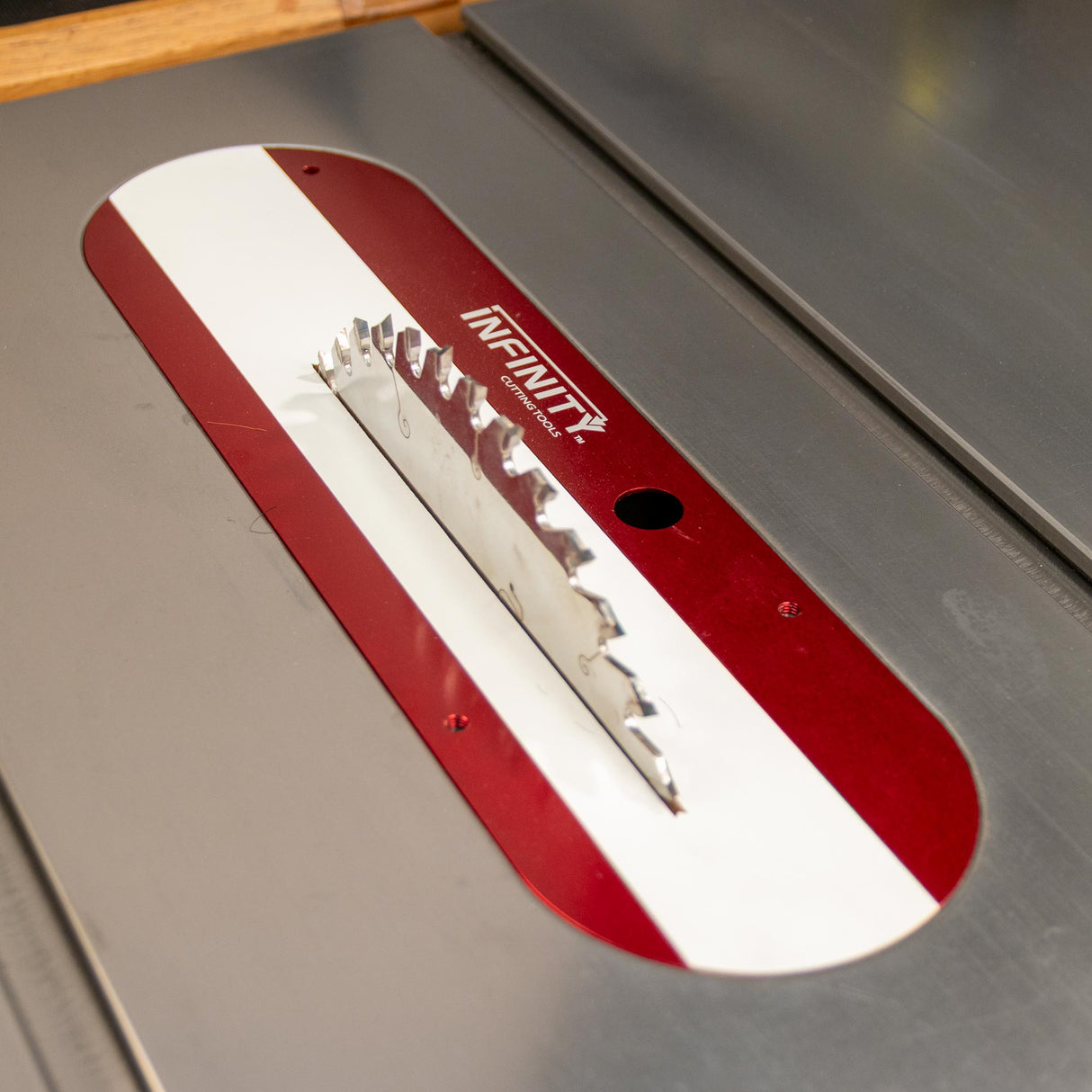 Table saw blade with red zero clearance insert for precise woodworking cuts