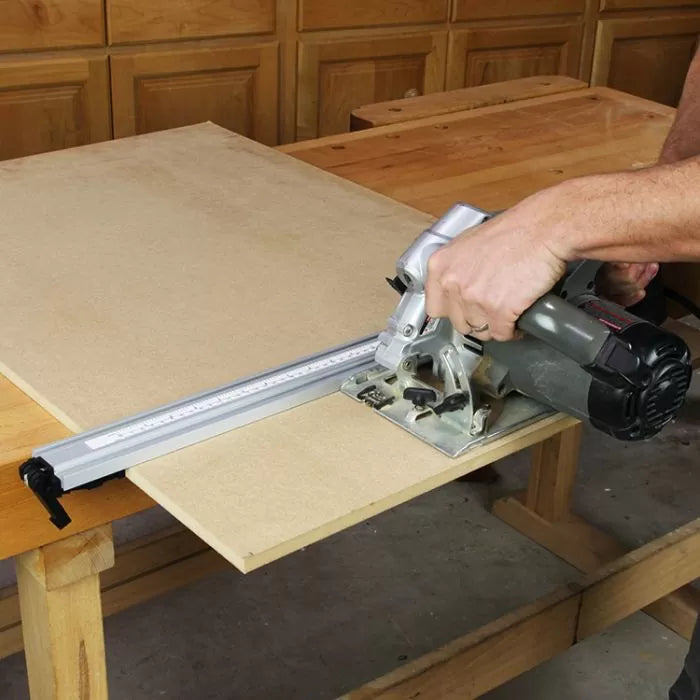 Circular saw with guide rail cutting sheet wood on workbench in woodworking shop