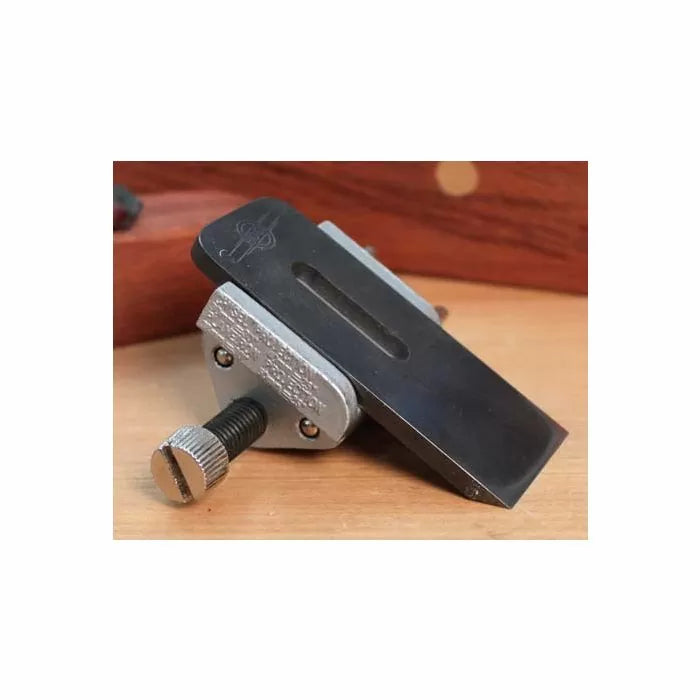 Woodworking honing guide tool with metal clamp and adjustment screw on a wooden surface