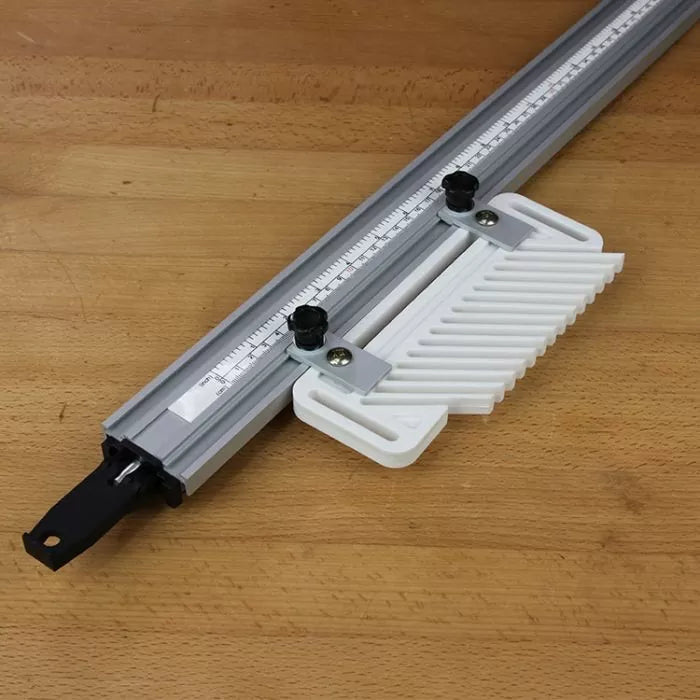 Router table fence with adjustable featherboard and measurement scale on a wood surface