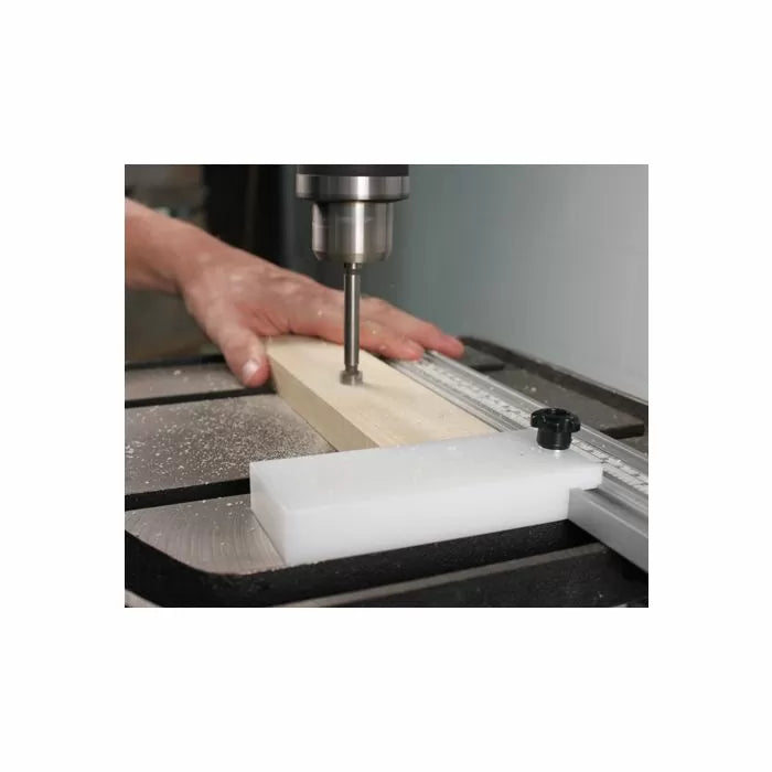Drill press drilling wood with fence stop block for precise woodworking cuts