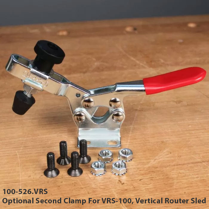 Toggle clamp with red handle and mounting hardware for vertical router sled on workbench