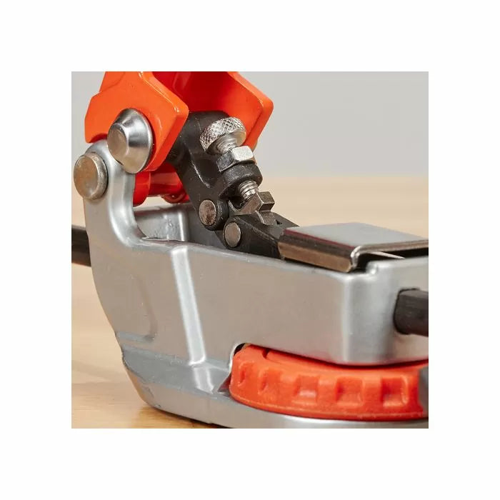 Close-up of a woodworking saw chain sharpener tool with orange and metal parts on a workbench