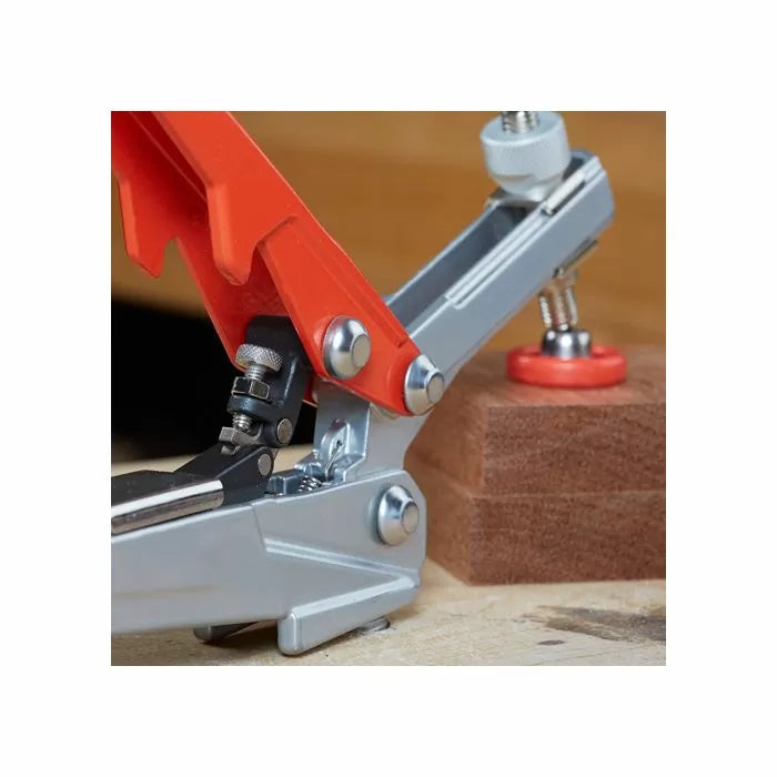 Toggle clamp securing a wood block on a workbench, woodworking tool close-up