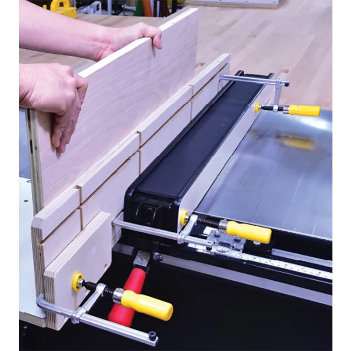 Woodworker using dado sled jig and clamps on table saw for precise woodworking cuts