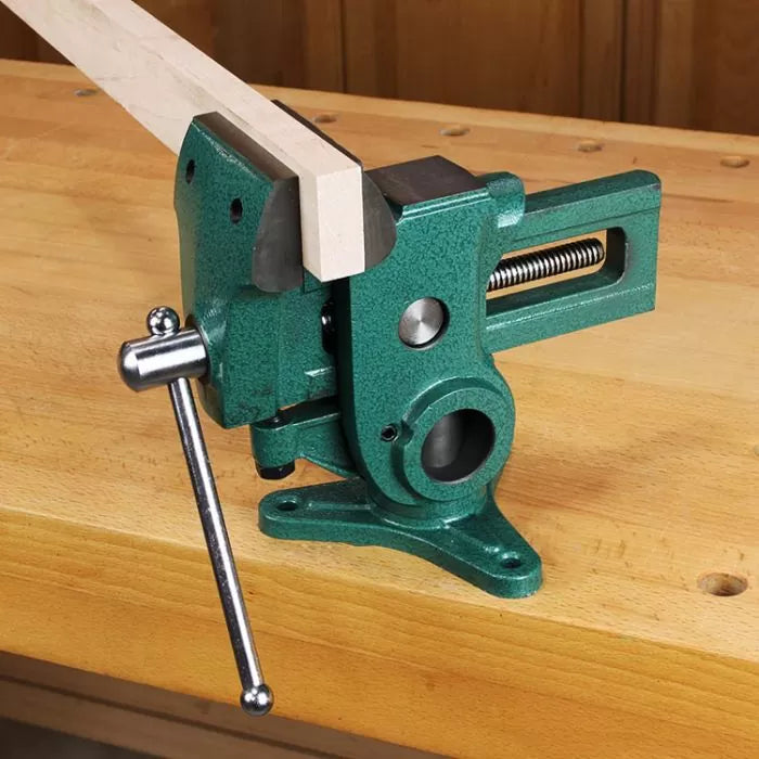 Green woodworking bench vise clamping a wooden board on a workbench