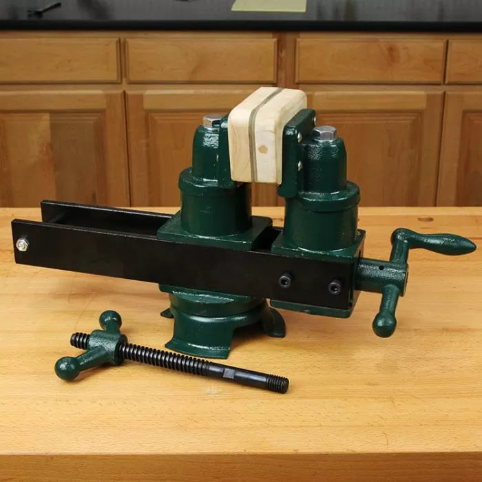 Green woodworking bench vise with wooden jaw on workbench in workshop setting