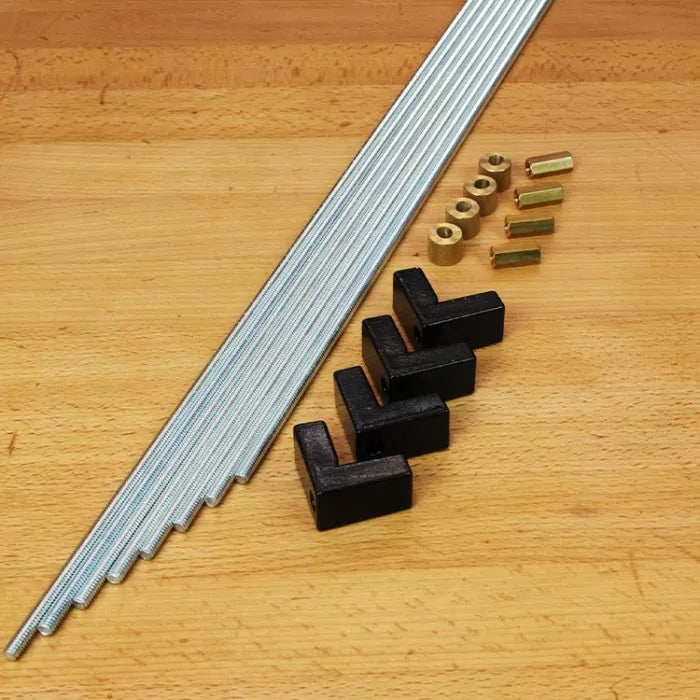 Woodworking jig hardware kit with threaded rods, black plastic brackets, and brass fittings on a workbench.