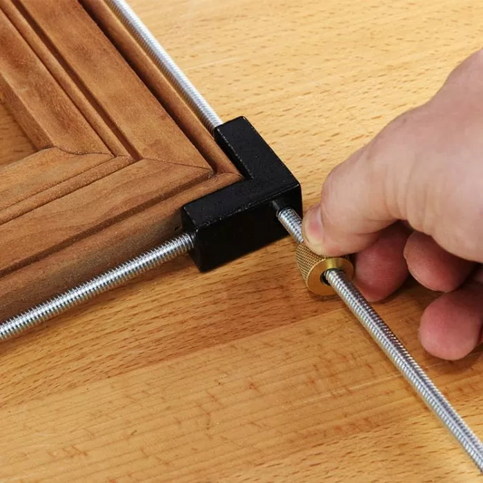 Corner clamp holding wood frame on workbench for precise woodworking assembly