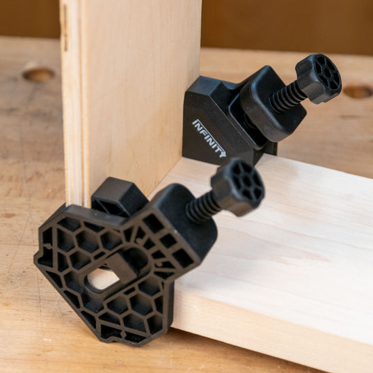 Corner clamps securing two wooden boards at a right angle on a workbench