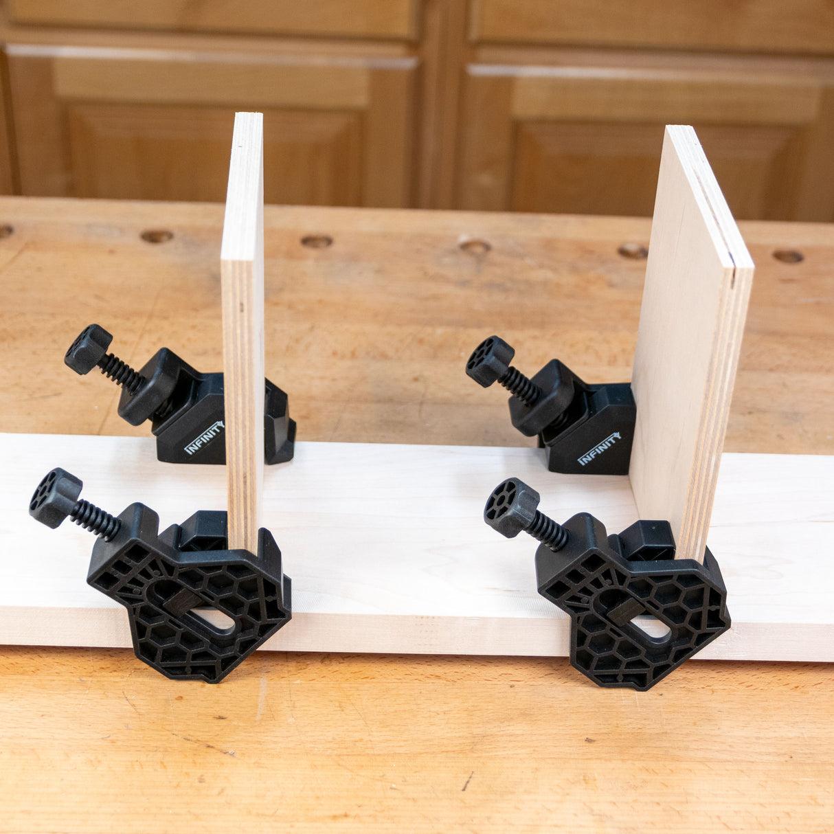 Corner clamps securing wood panels on a workbench for precise 90-degree woodworking joints