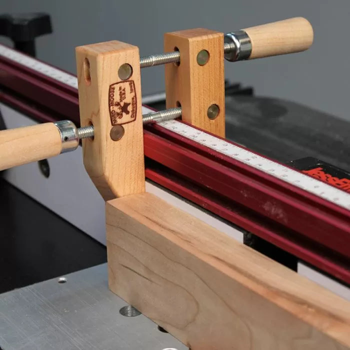 Wooden handscrew clamp holding a board against a router table fence with measuring scale