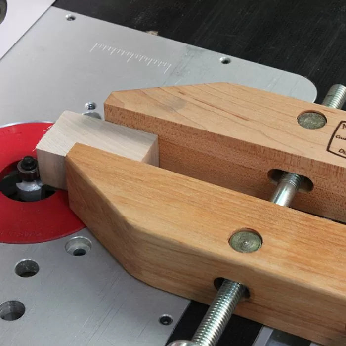 Woodworking router table with wooden hand screw clamp securing a wood block near router bit