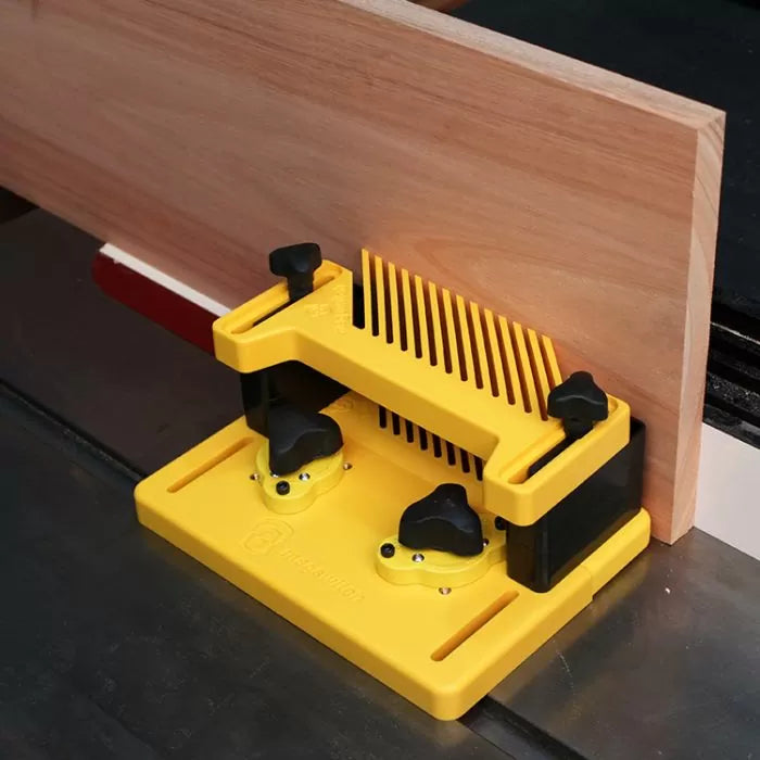 Yellow woodworking featherboard holding wood against a table saw fence for precise cutting