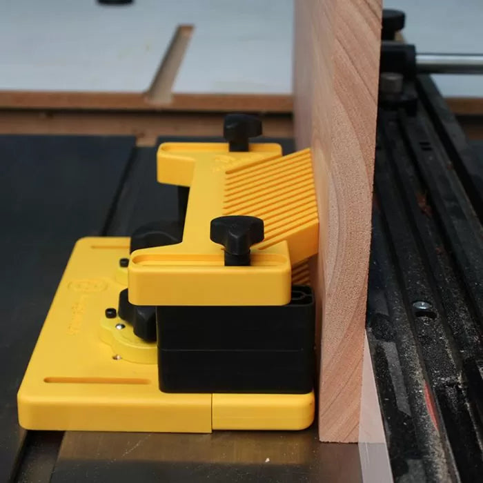 Yellow table saw featherboard holding wood securely for precise woodworking cuts