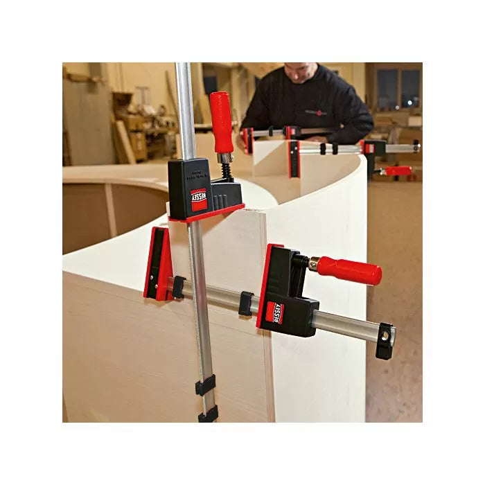 Woodworking parallel clamps securing curved plywood in workshop setting