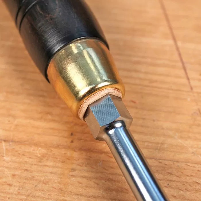 Close-up of woodworking screwdriver handle with brass ferrule on wooden workbench