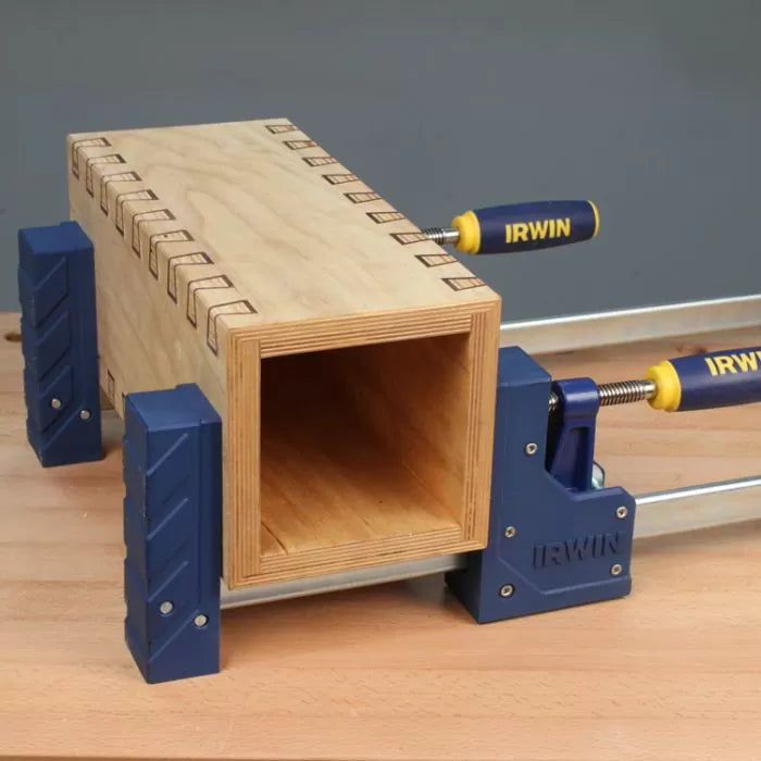 Wooden box with finger joints clamped using Irwin bar clamps on a workbench