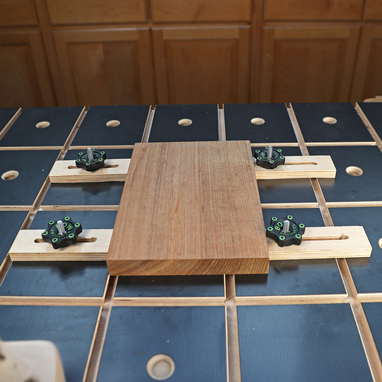 Woodworking workbench with toggle clamp hold-downs securing a wood board