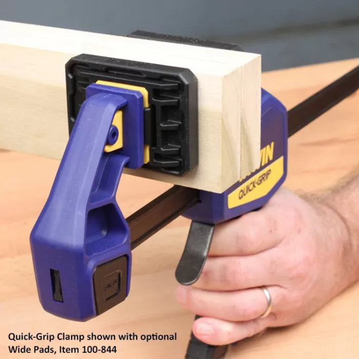 Quick-Grip clamp with optional wide pads securing a wood block on a workbench