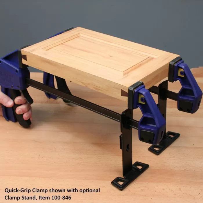 Quick-Grip clamps with black clamp stand securing wooden panel on a workbench