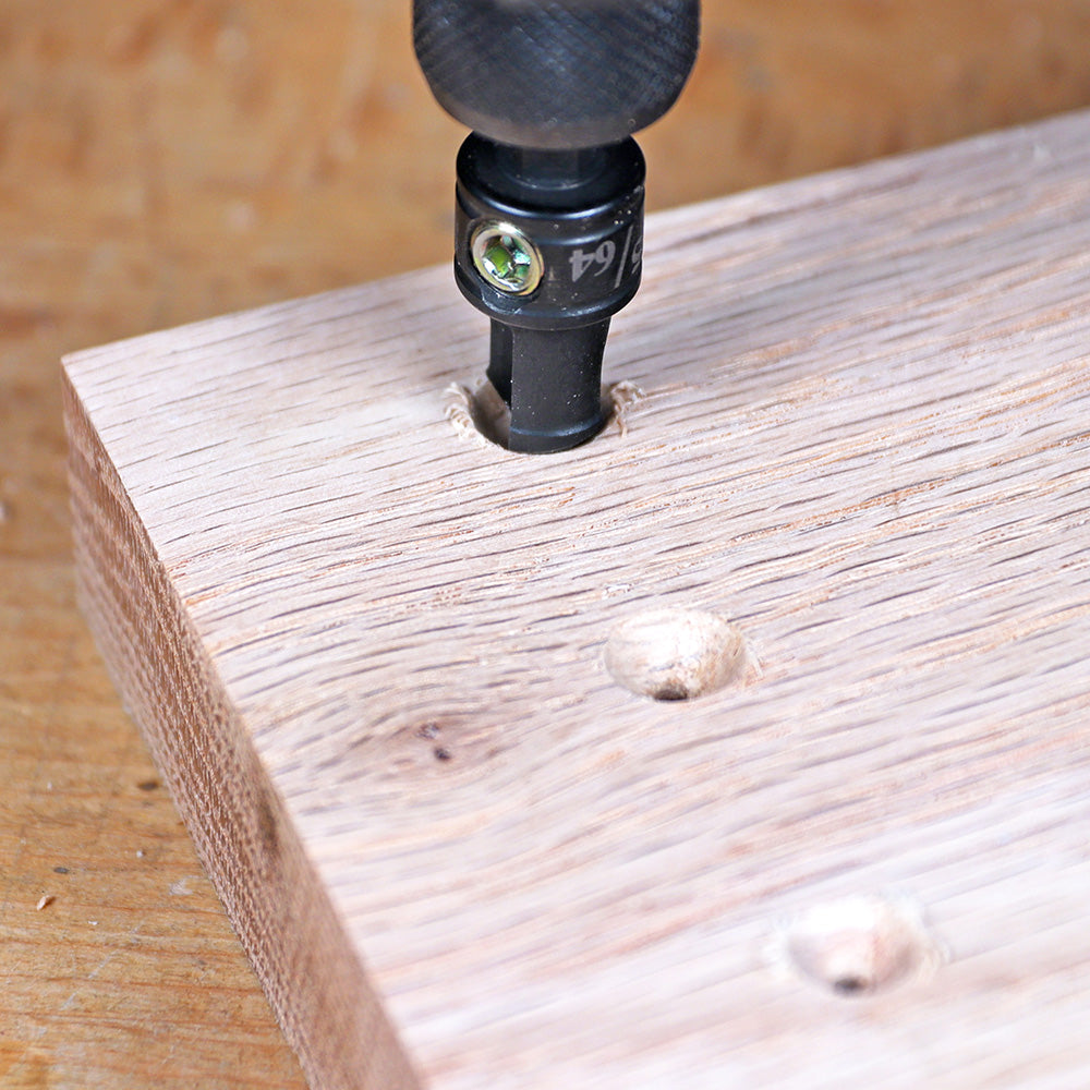 Pocket hole drill bit drilling angled holes in a wooden board for woodworking joinery.