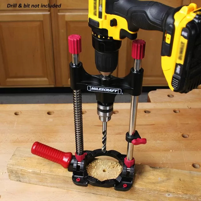 Drill guide jig for woodworking, mounted on a wooden workbench with drill attached.
